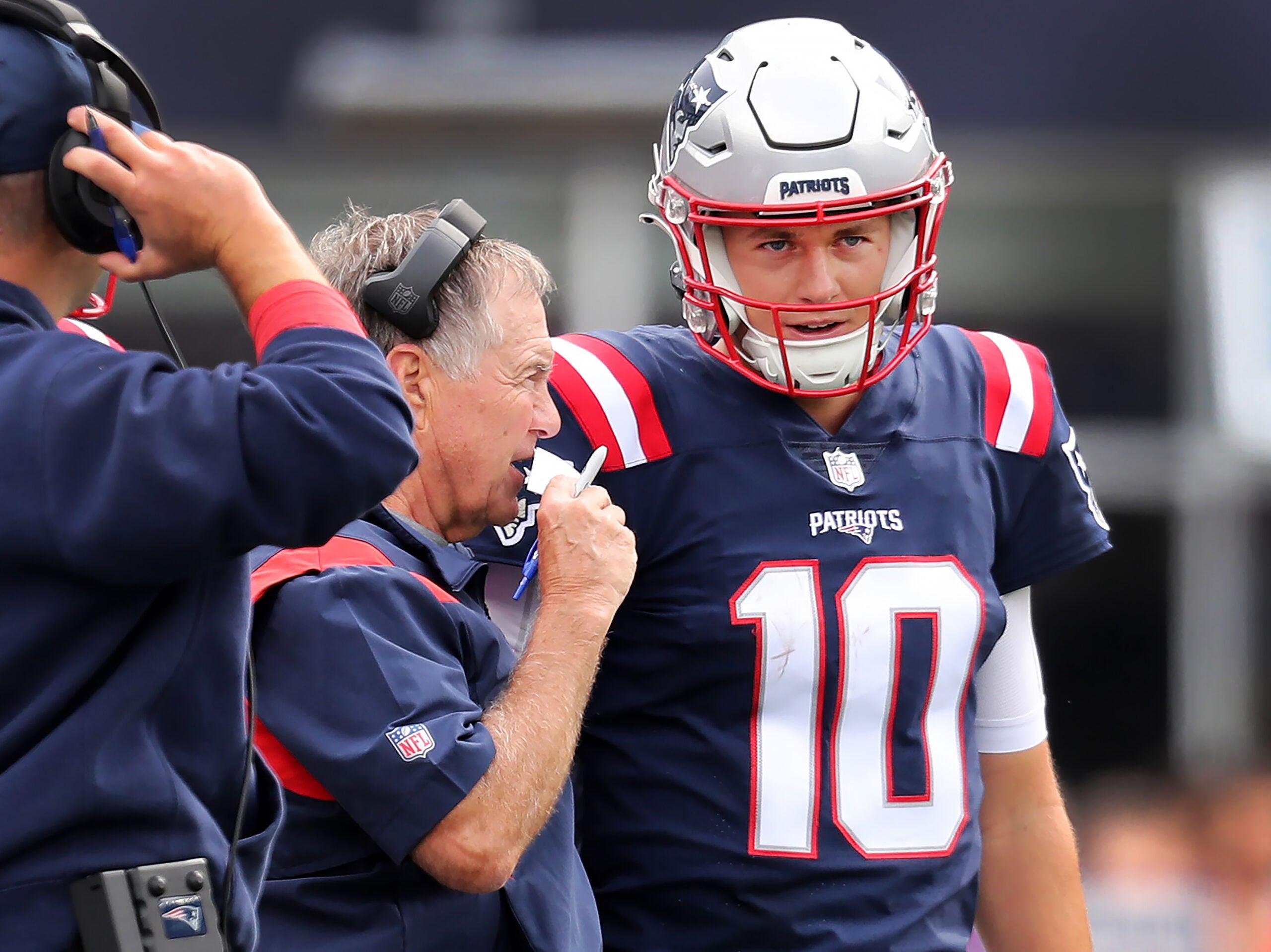 Patriots quarterback Mac Jones (right) listens to head coach Bill Belichick (left) on the sidelines. Joe Judge is at far left. The New England Patriots hosted the Baltimore Ravens in a regular season NFL football game at Gillette Stadium.