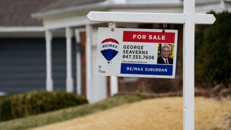 A RE/Max for sale sign in front of a home with a yellow lawn is used in a story on mortgage rates.
