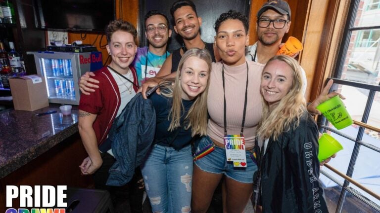 Seven smiling people celebrate the Pride Bar Crawl in Boston