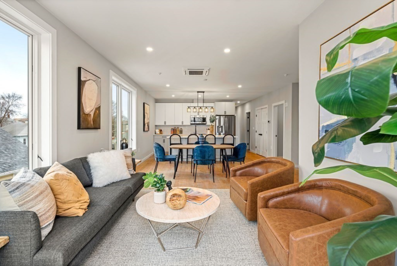 The living space has light gray walls, hardwood floors, and picture windows. 