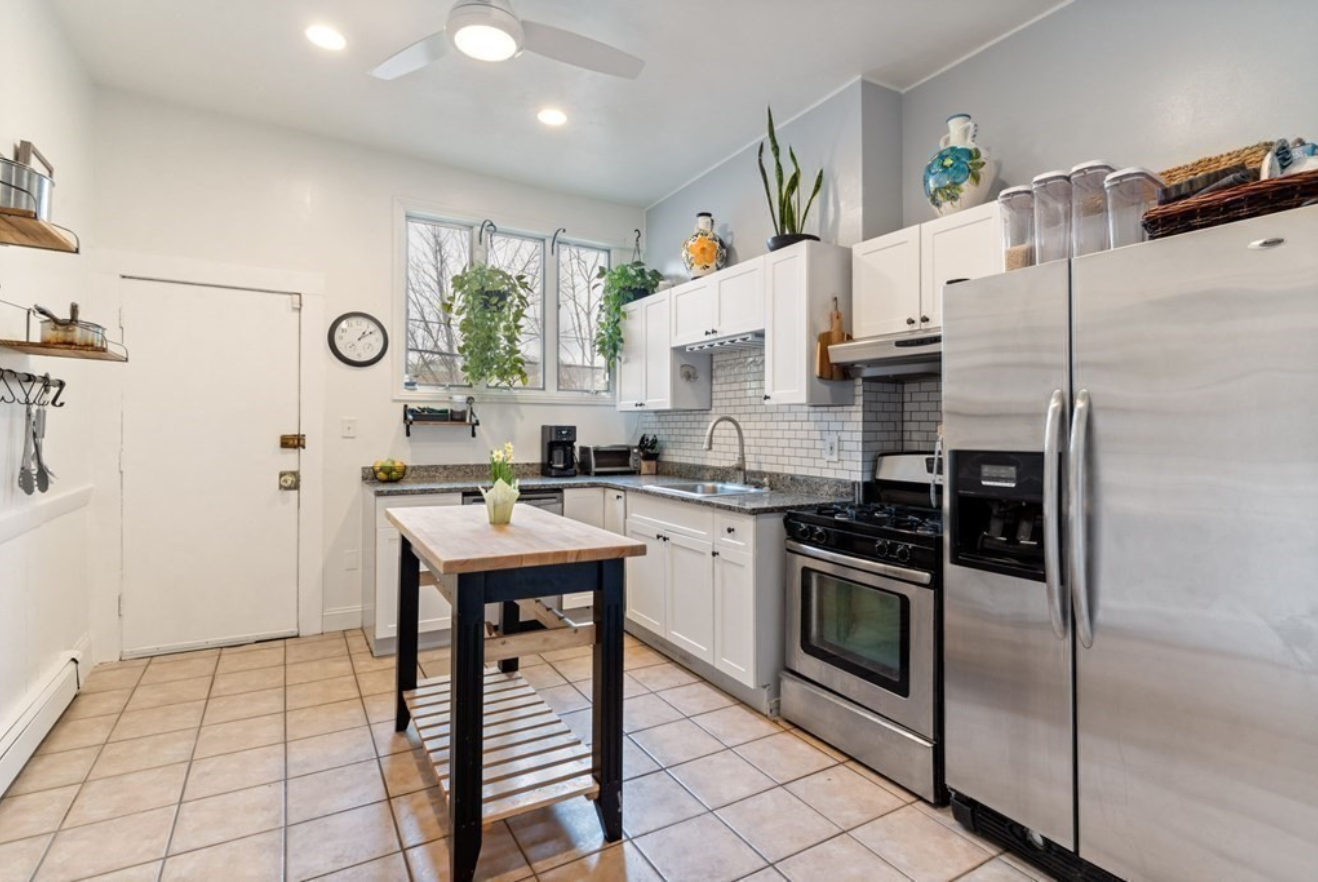 The kitchen has white Shaker-style cabinets, stainless steel appliances, and a butcher's block.