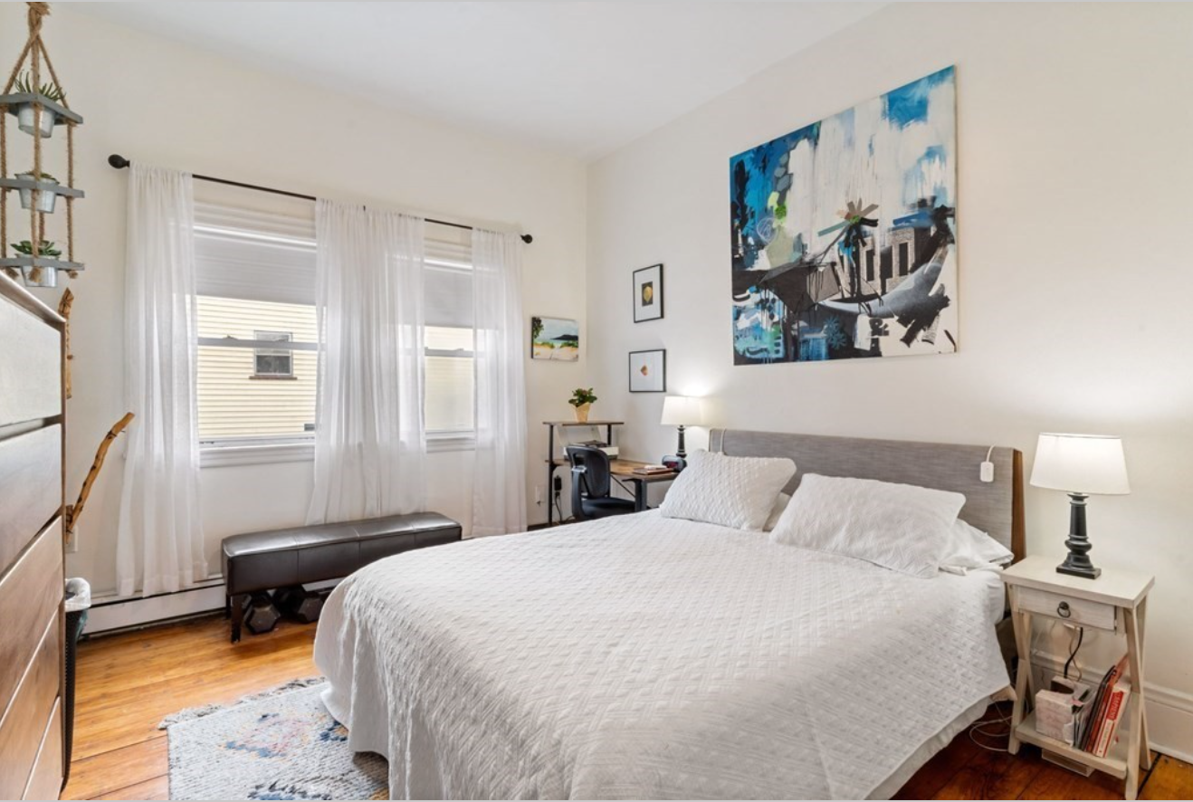 The bedroom has two single-hung windows and cream-colored walls.