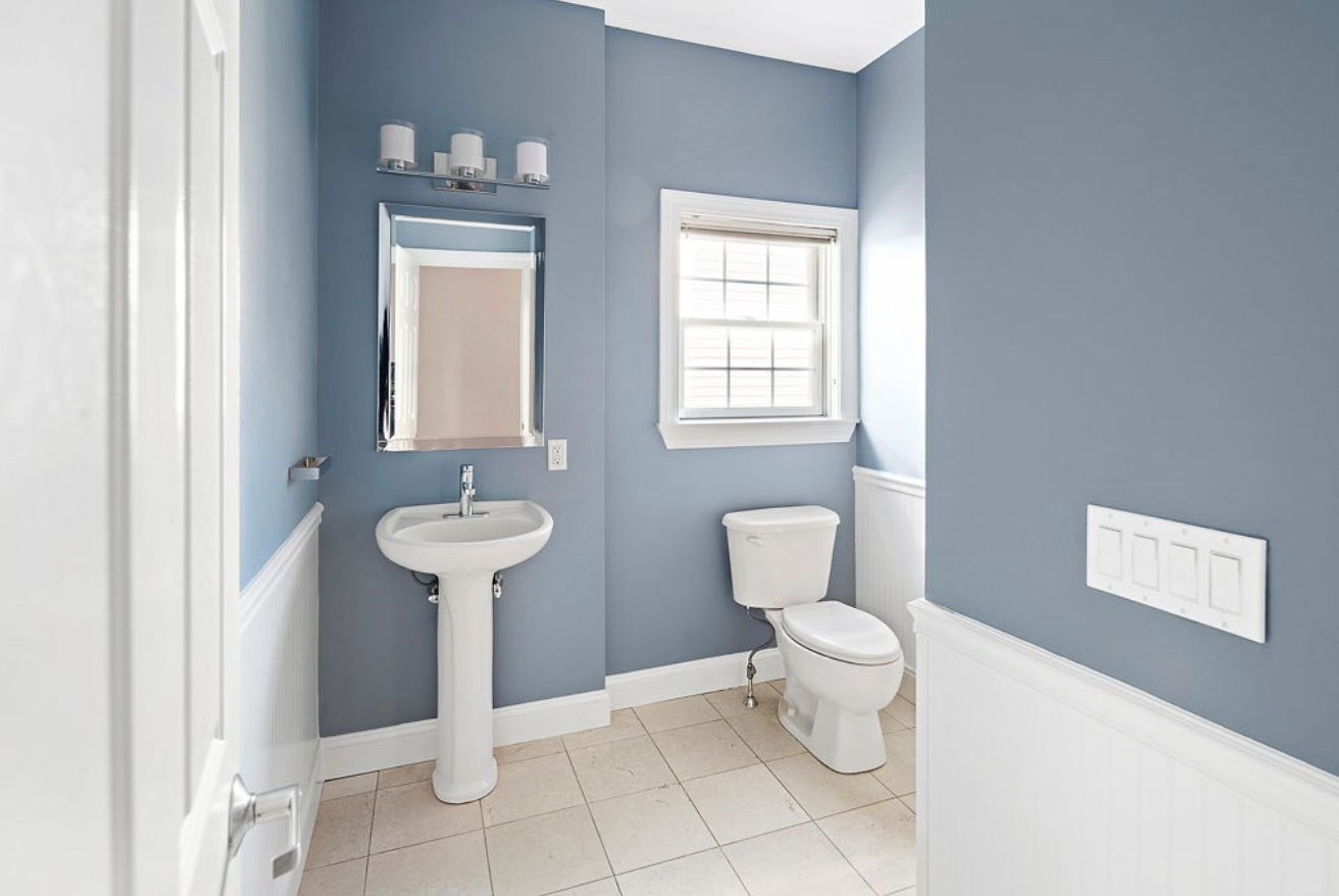 One bathroom has a single vanity and light blue-grey walls.