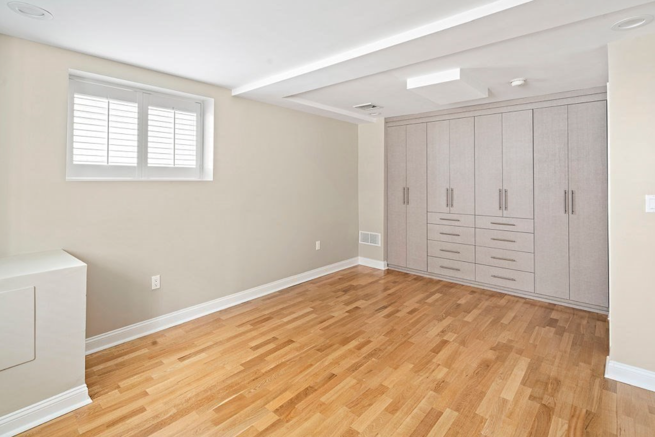 One bedroom has floor-to-ceiling built-in cabinets, beige walls, and hardwood floors.