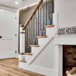 Under a staircase, a pet nook with brick walls and a 'dog house' sign overhead.