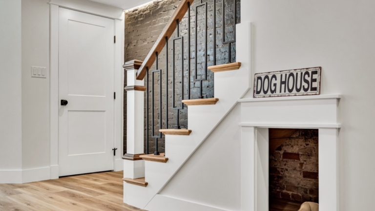 Under a staircase, a pet nook with brick walls and a 'dog house' sign overhead.