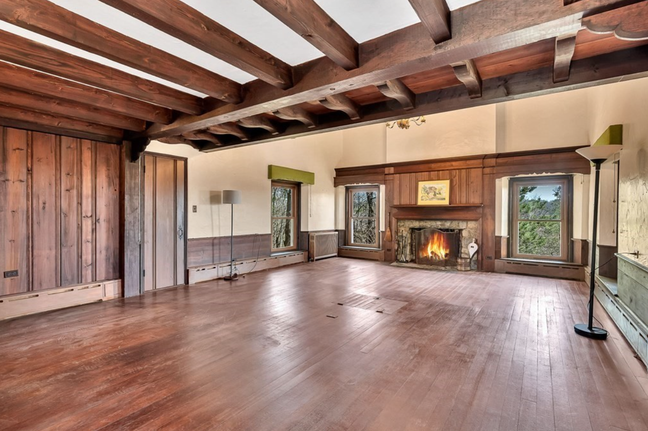 Living room with hardwood floors, exposed wood ceilings beams, and a fireplace.