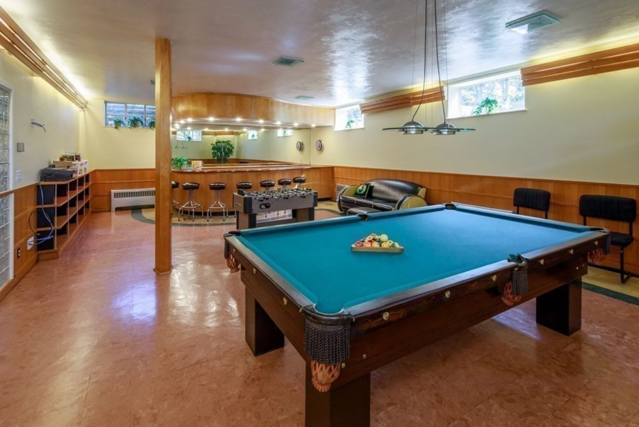 Basement with mid-century wood paneling and a bar with seating for seven.
