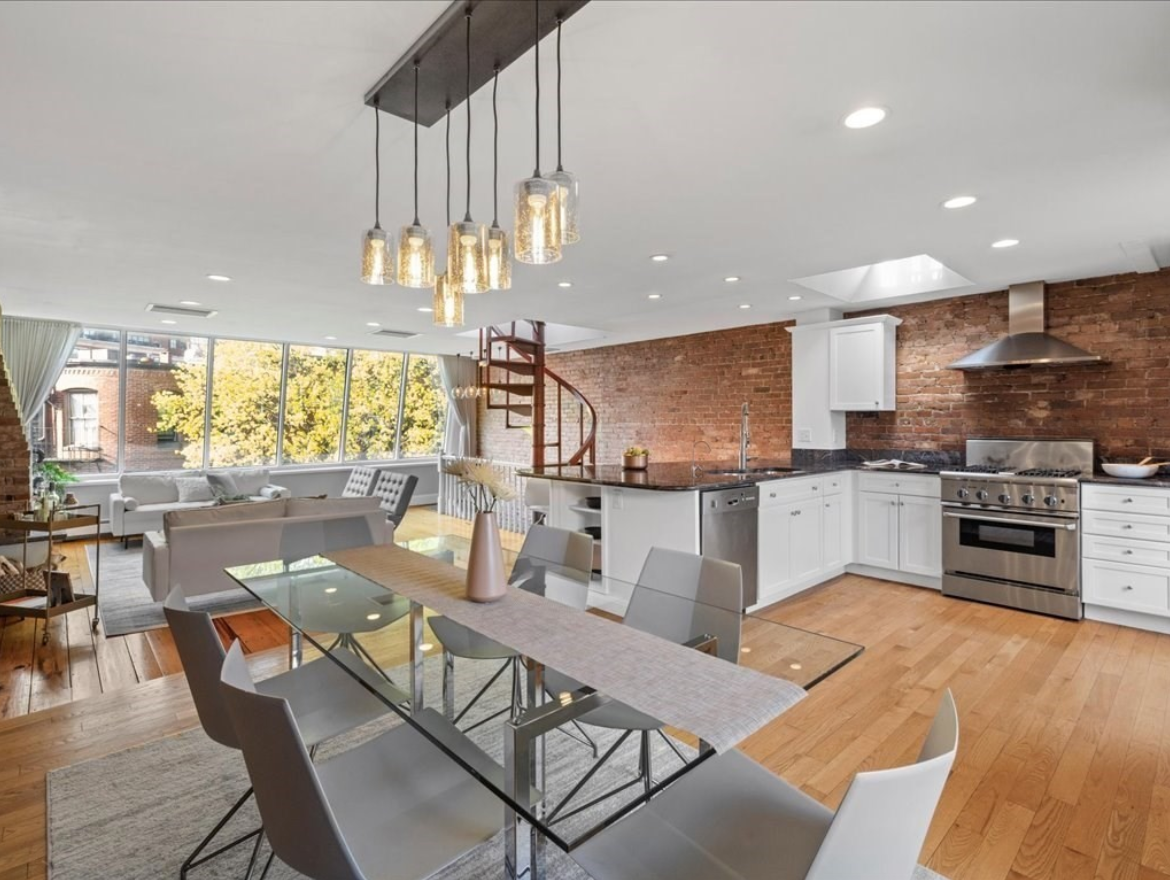 Kitchen and dining area with hardwood floors, exposed brick walls, and pendant lighting.