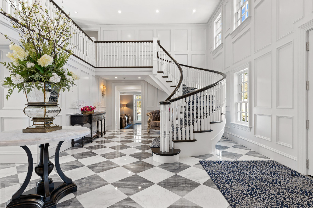 Foyer with checkered tile flooring, white walls, vaulted ceilings, and a winding staircase.