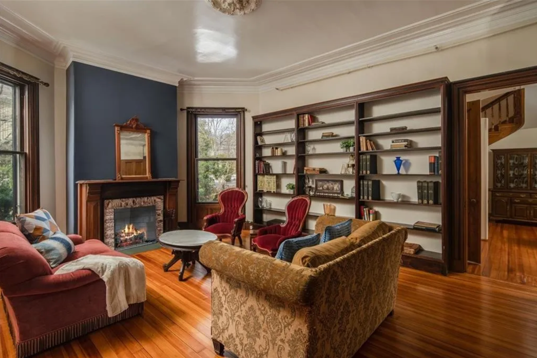 The living room has built-in shelving and a dark blue accent wall, as well as a gas fireplace and hardwood floors.