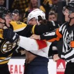 Trent Frederic of the Bruins and Ryan Lomberg of the Panthers are separated by referee Gord Dwyer.