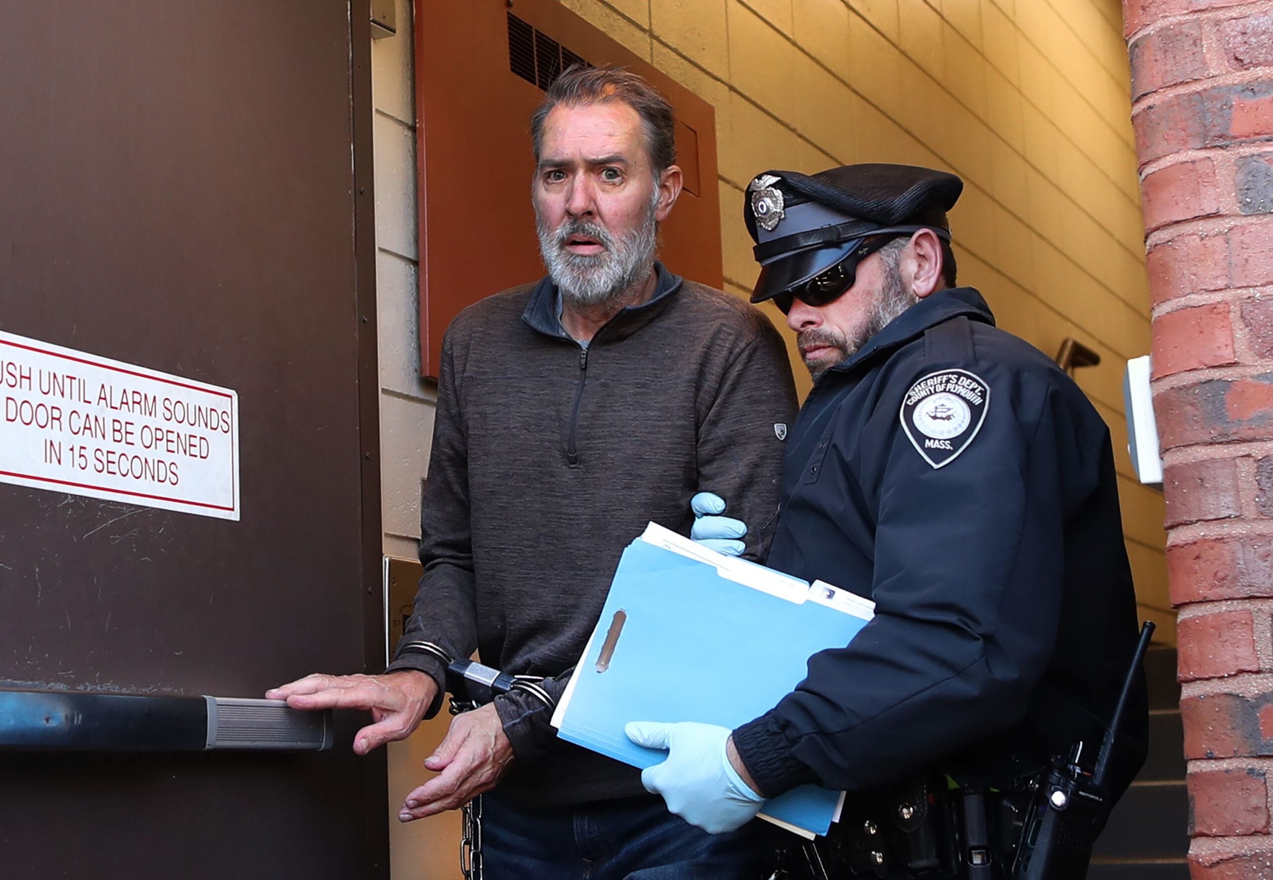 Bradley Rein, 53, of Hingham, is led out of Hingham District Court on Nov. 22, 2022 after his arraignment for crashing his SUV into the Hingham Apple store.