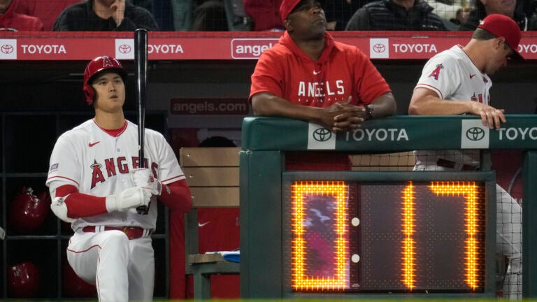 Los Angeles Angels designated hitter Shohei Ohtani, left, stands near the pitch clock during the sixth inning of a baseball game against the Washington Nationals in Anaheim, Calif., Monday, April 10, 2023.