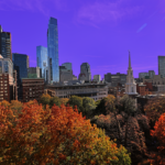 The Boston skyline with autumn trees in the foreground. The sky is tinted purple.
