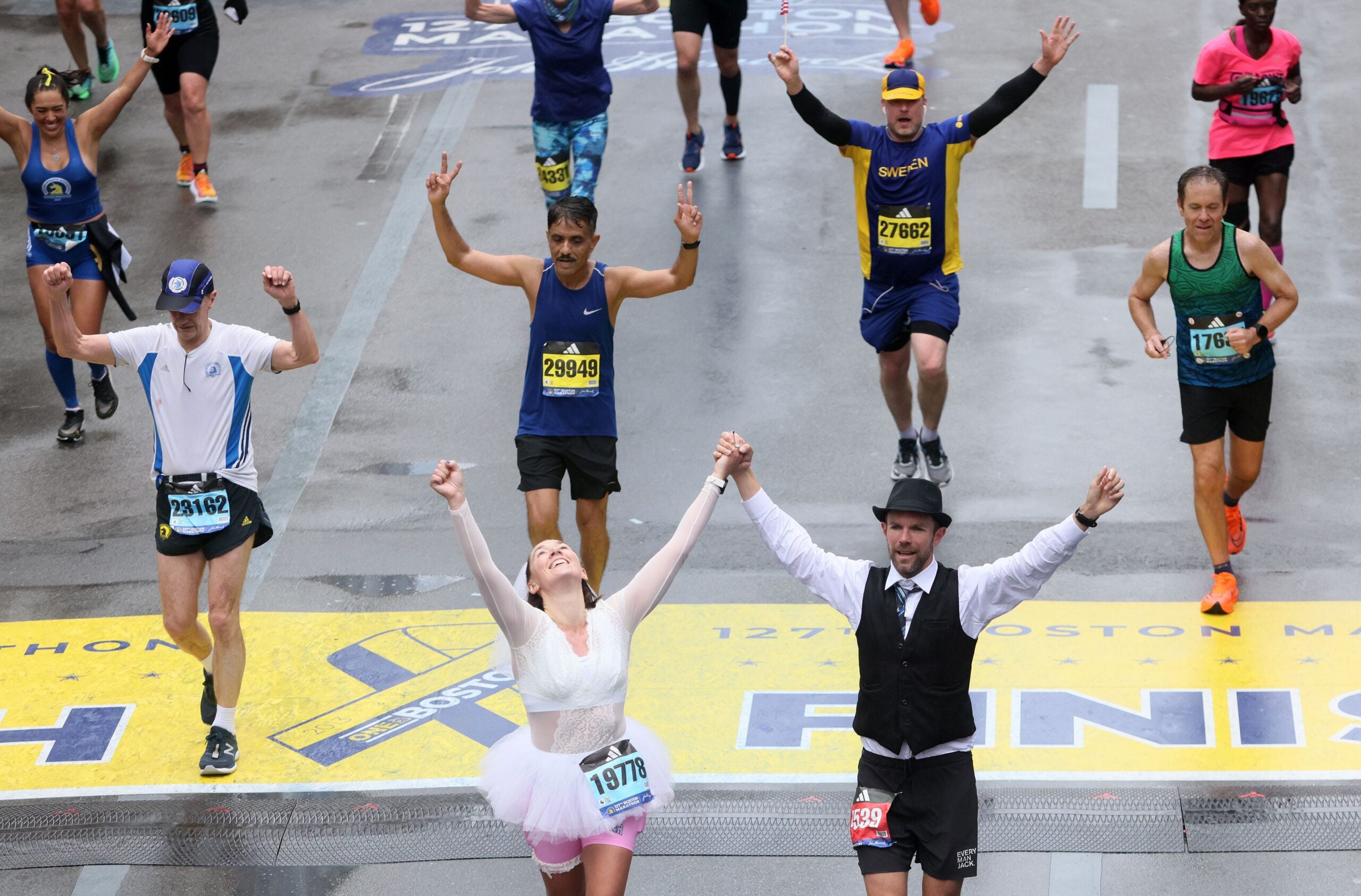 Runners celebrate as they cross the Finish Line of the Boston Marathon on the ten year anniversary of the Marathon bombing.