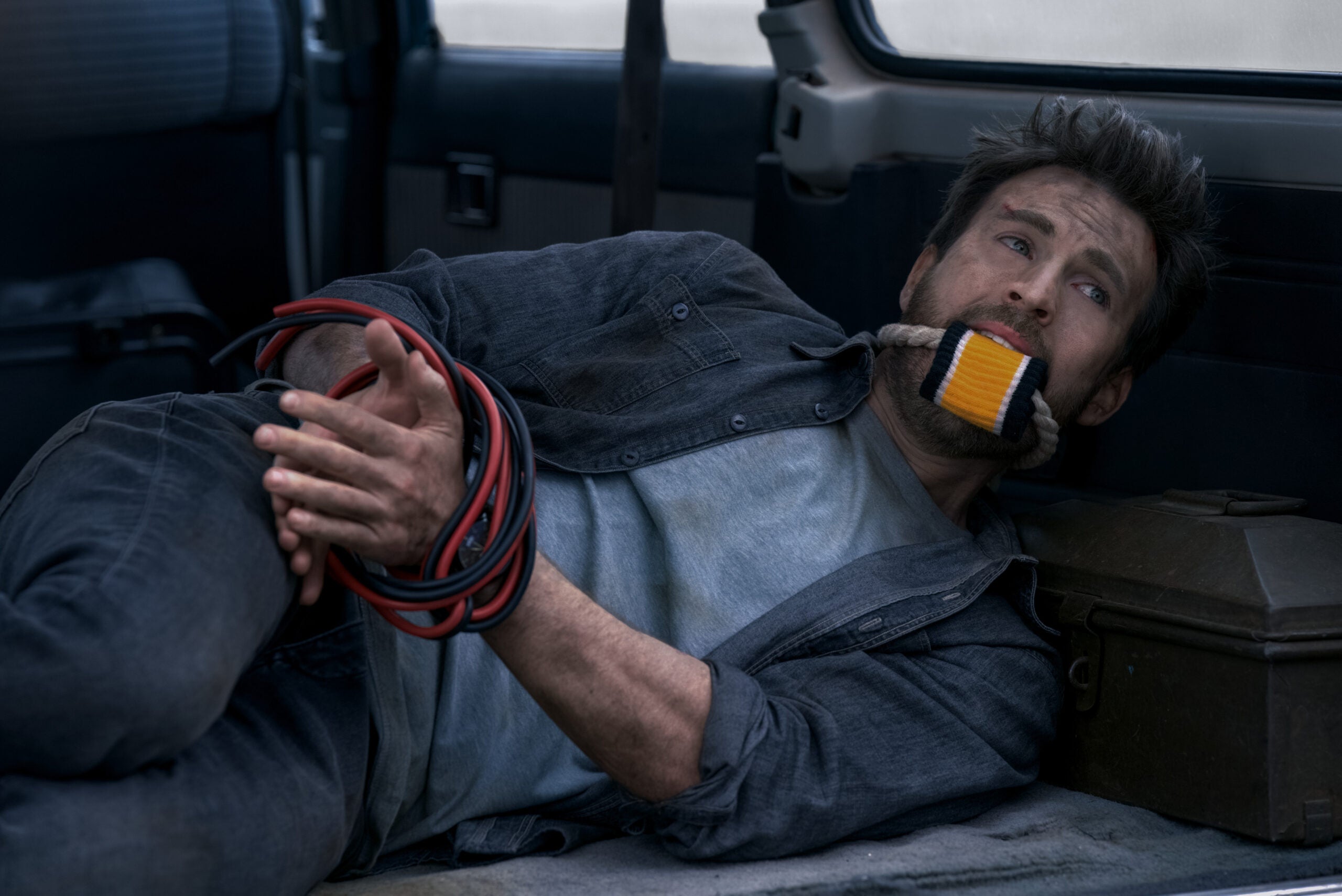 Chris Evans lying bound and gagged in the trunk of a car in the movie "Ghosted."