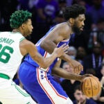 Sixer center Joel Embiid guarded by Celtics guard Marcus Smart.