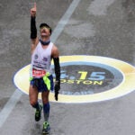 Fernando Ferreira celebrates after crossing the finish line as rain falls.
