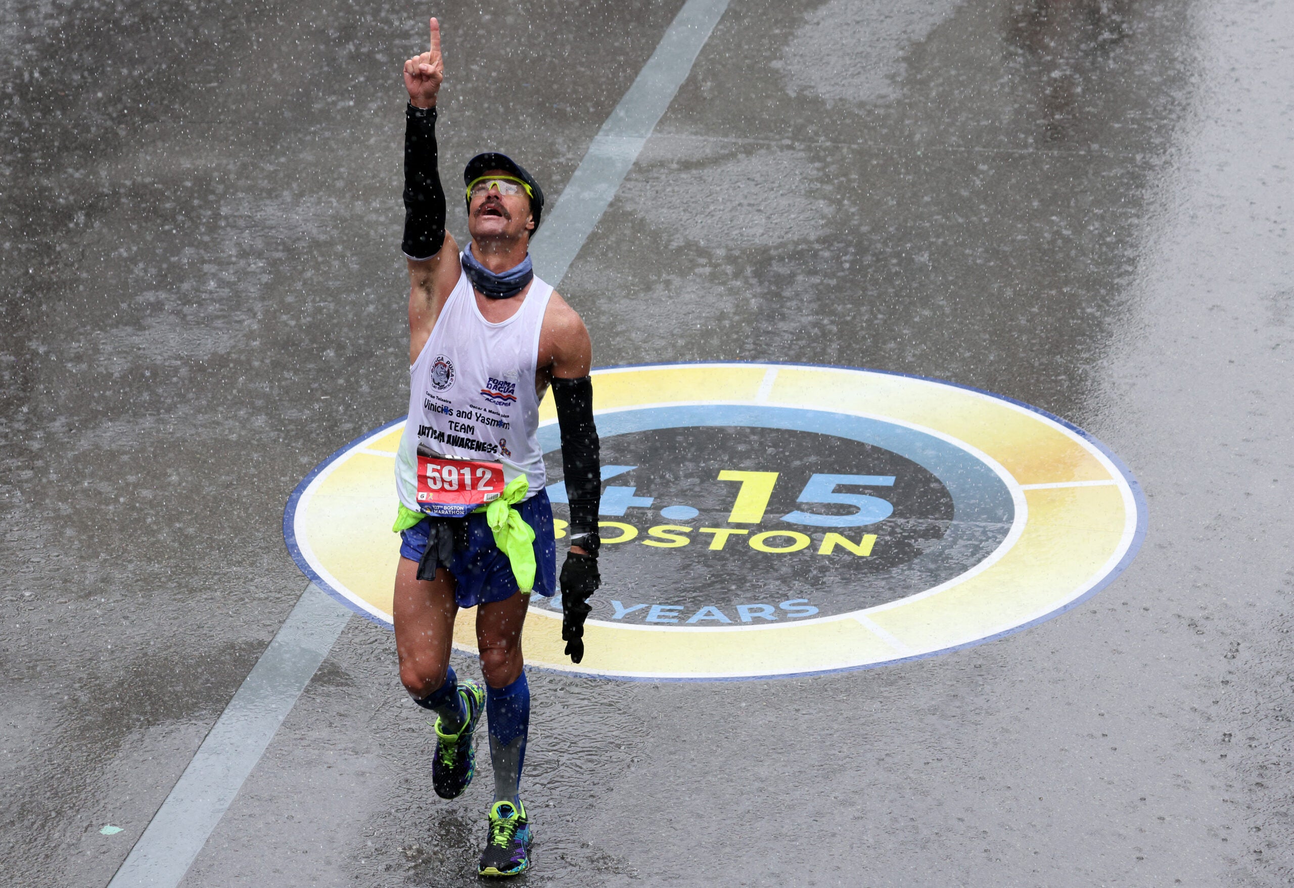 Fernando Ferreira celebrates after crossing the finish line as rain falls.