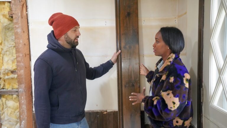 A man in a blue parka and red ski hat and jeans. And a woman in a floral sweater and jeans.