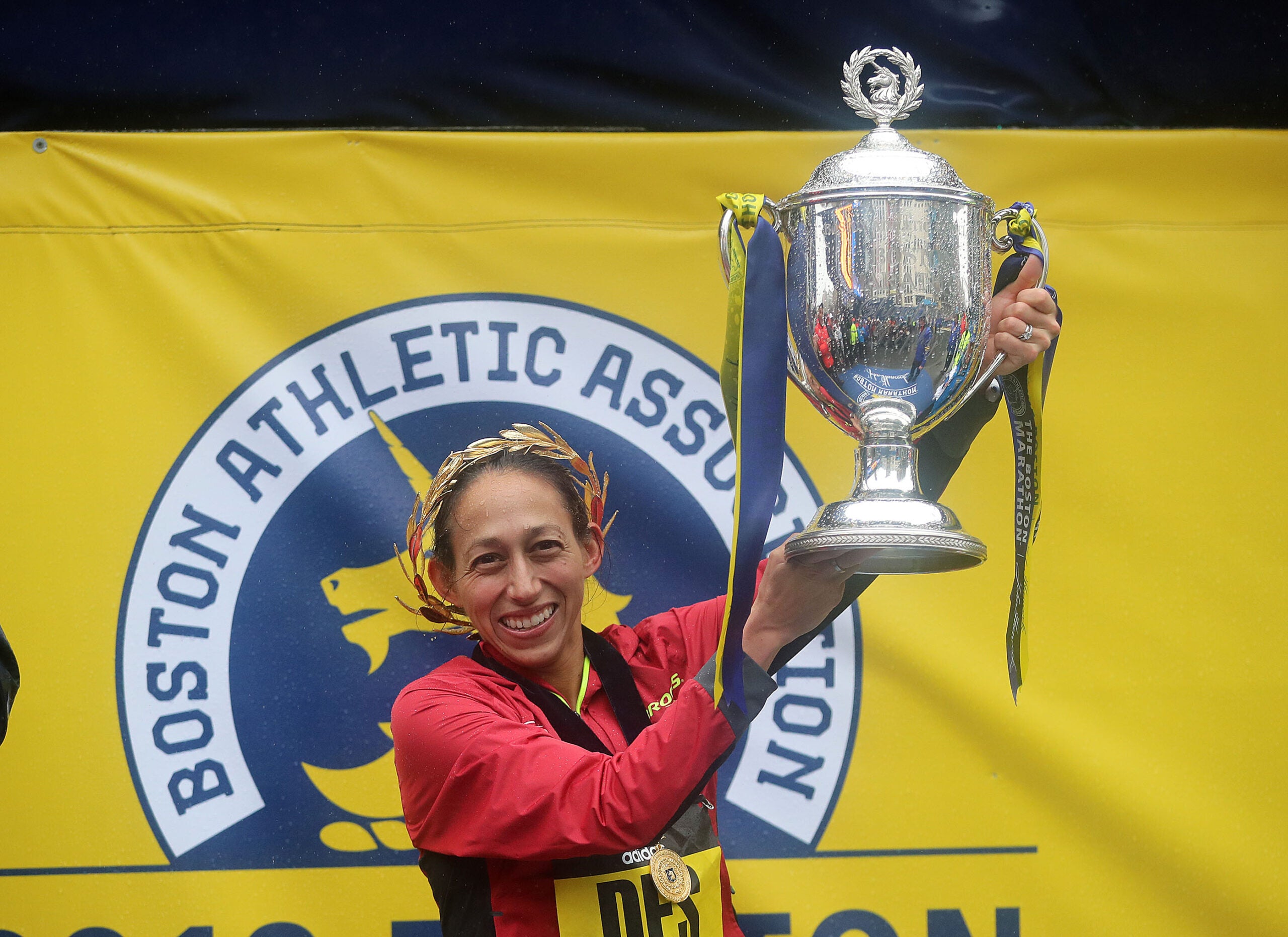 Des Linden holds up the Champions trophy after the 2018 Boston Marathon.