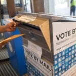 A voter casts a ballot for a different election at a vote-by-mail dropbox at Boston City Hall.
