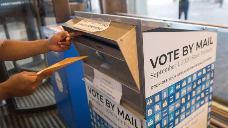 A voter casts a ballot for a different election at a vote-by-mail dropbox at Boston City Hall.