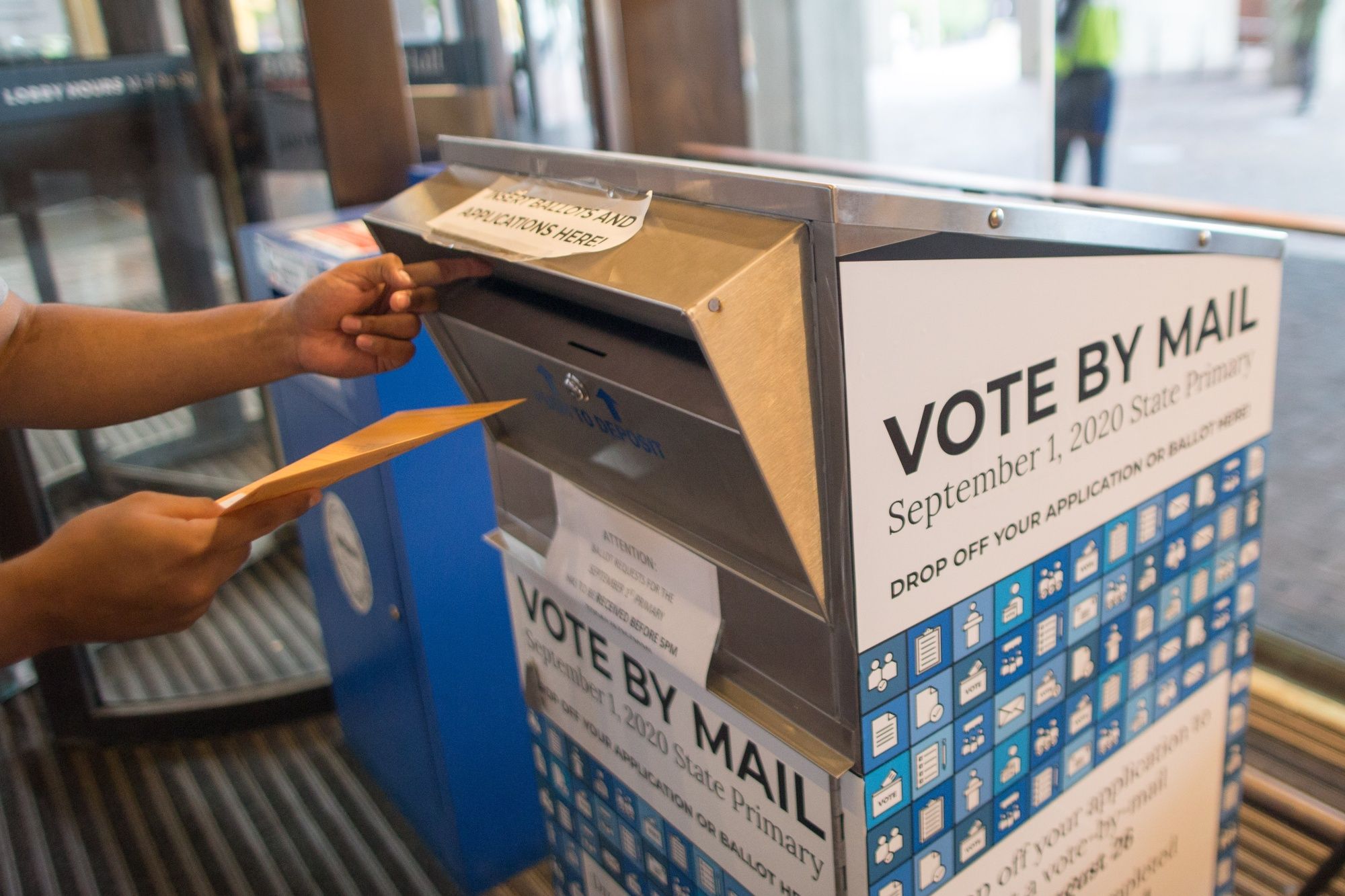 A voter casts a ballot for a different election at a vote-by-mail dropbox at Boston City Hall.