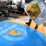 Workers paint on the unicorn logo at the start line of the Boston Marathon in Hopkinton.