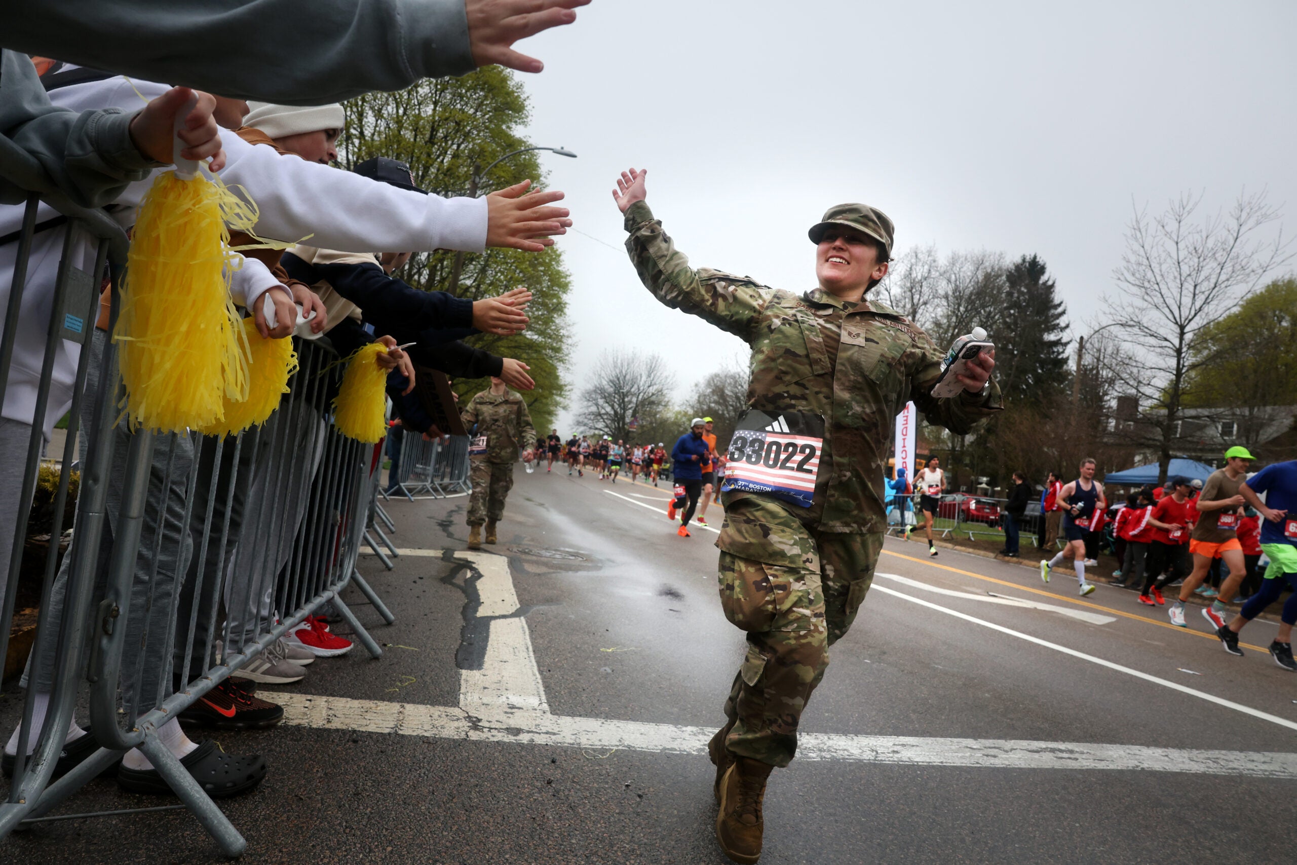 A military participant greets the spectators at Heartbreak Hill during the running of the  127th Boston Marathon in Newton, MA on April 17, 2023. 