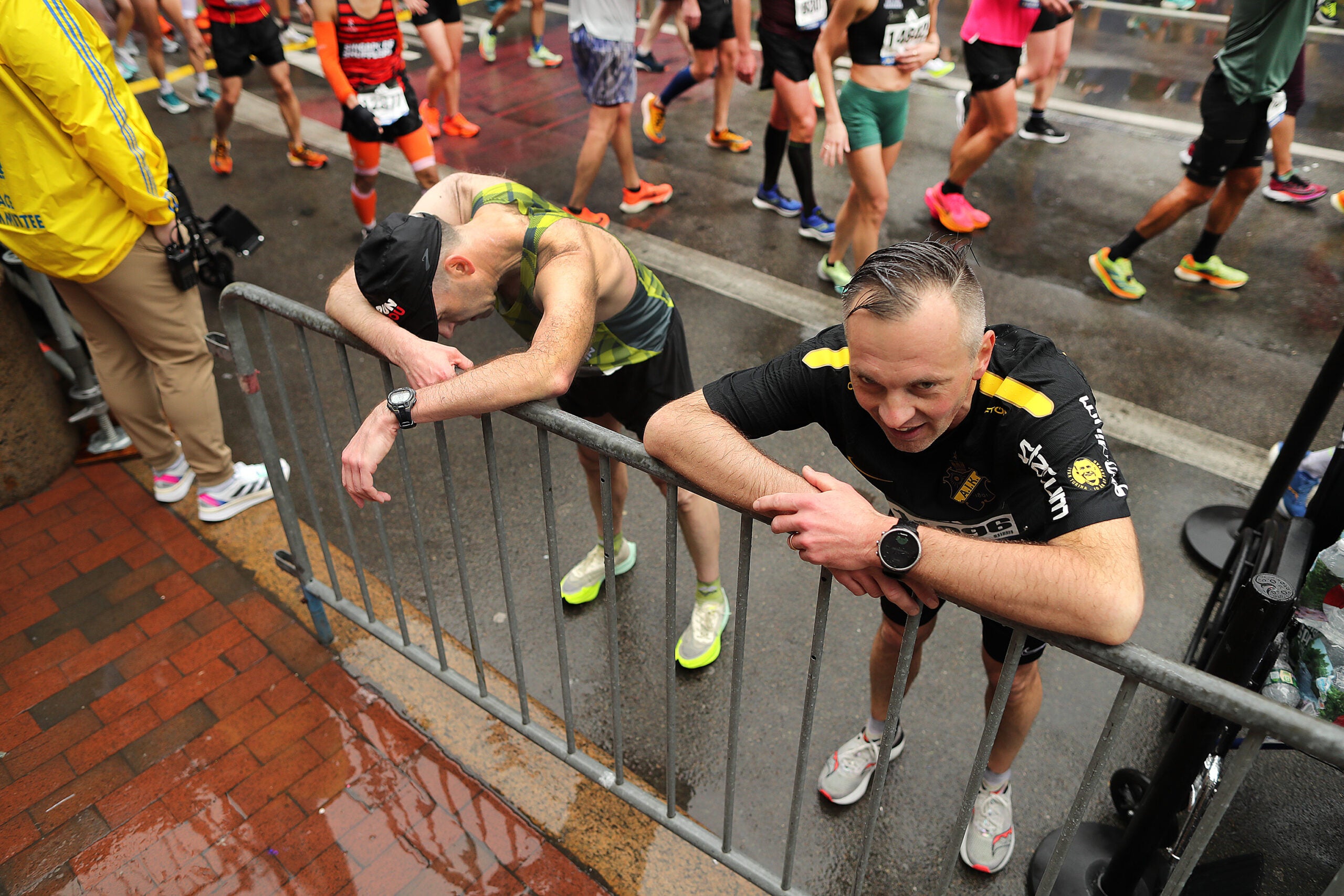 Two runners rest after crossing the Boston Marathon finish line. 