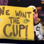 A young fan leans on the glass waiting for the Bruins to take the ice in pregame warmups.