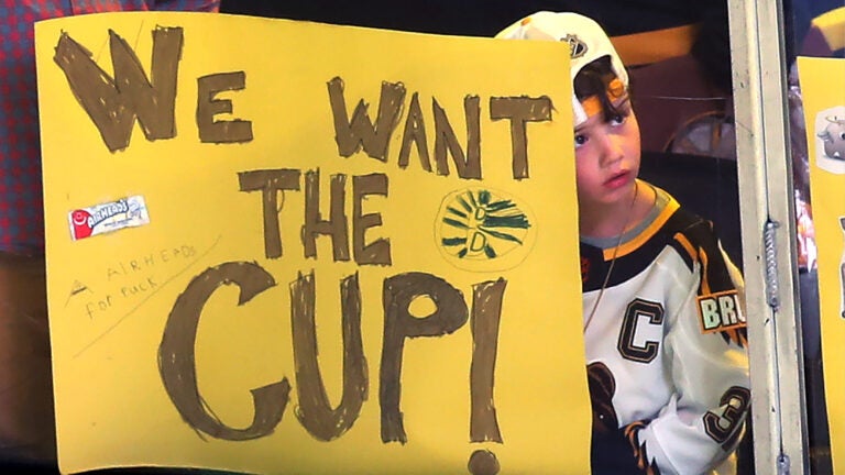 A young fan leans on the glass waiting for the Bruins to take the ice in pregame warmups.