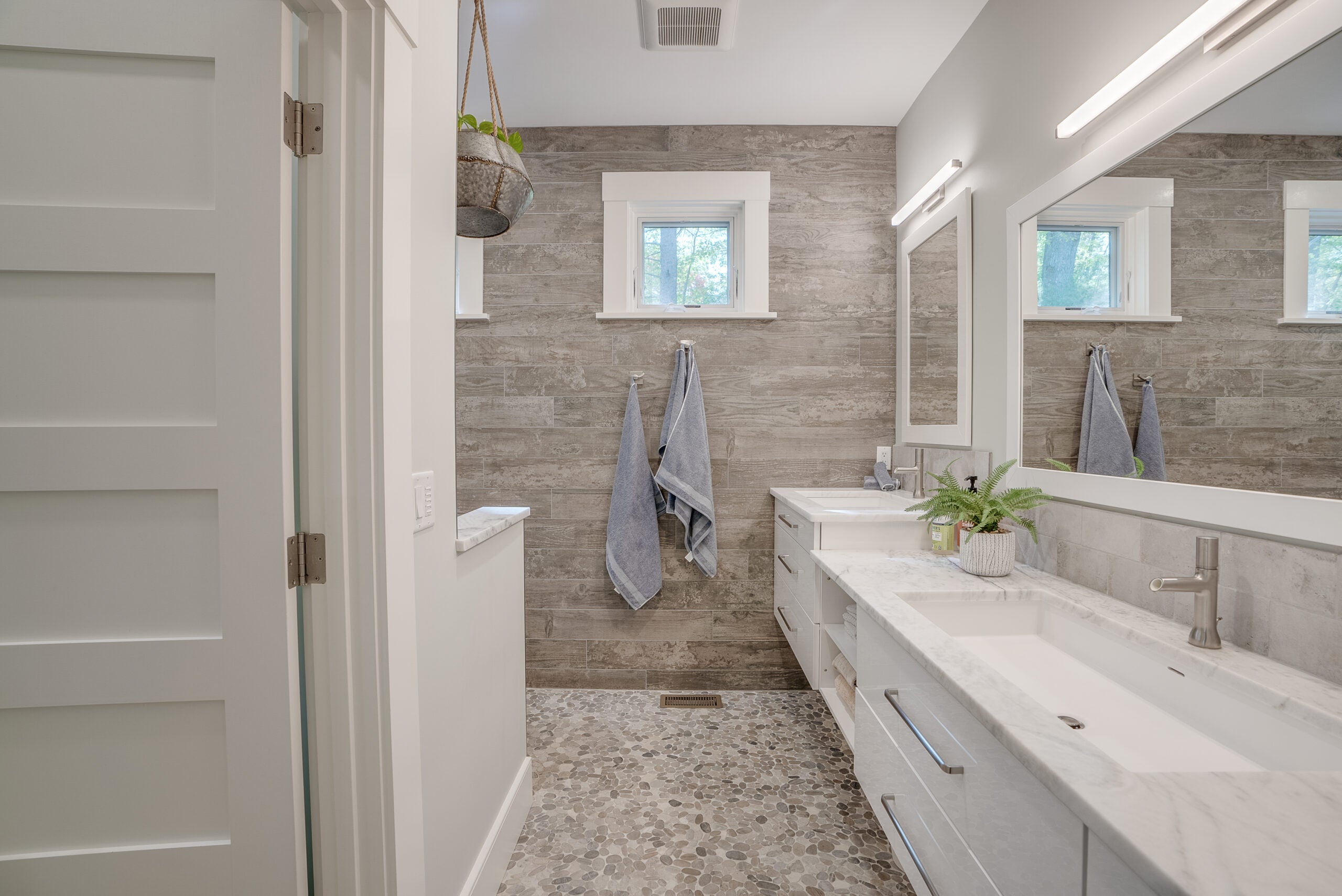 A bathroom with a floating double vanity that is long. The flooring is tile, as are the walls.