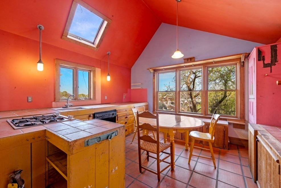 A bright coral room with a vaulted ceiling, numerous windows, a tile floor, and tile countertops.