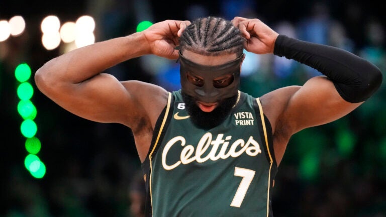 Celtics guard Jaylen Brown putting on his face mask.