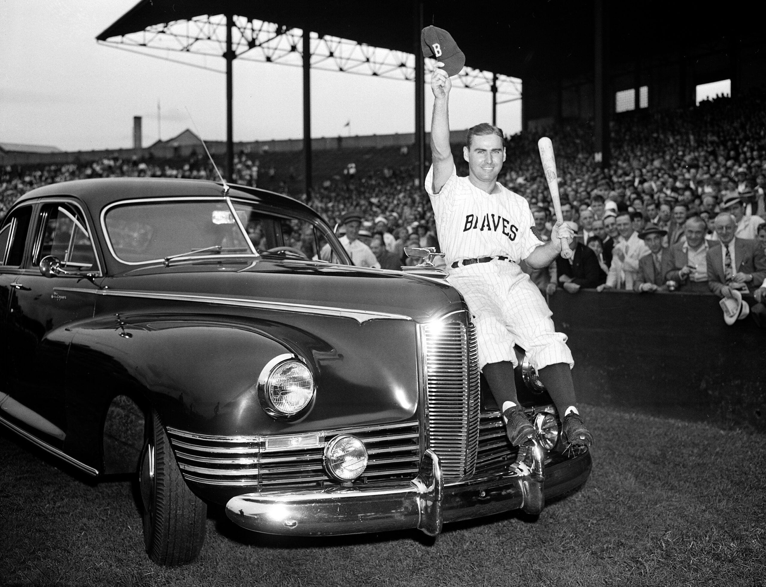 Boston Braves outfielder Tommy Holmes waves from the automobile presented to him on "Tommy Holmes Day."
