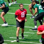 New York Jets quarterback Aaron Rodgers performs stretching drills with his teammates at the NFL football team's practice facility.