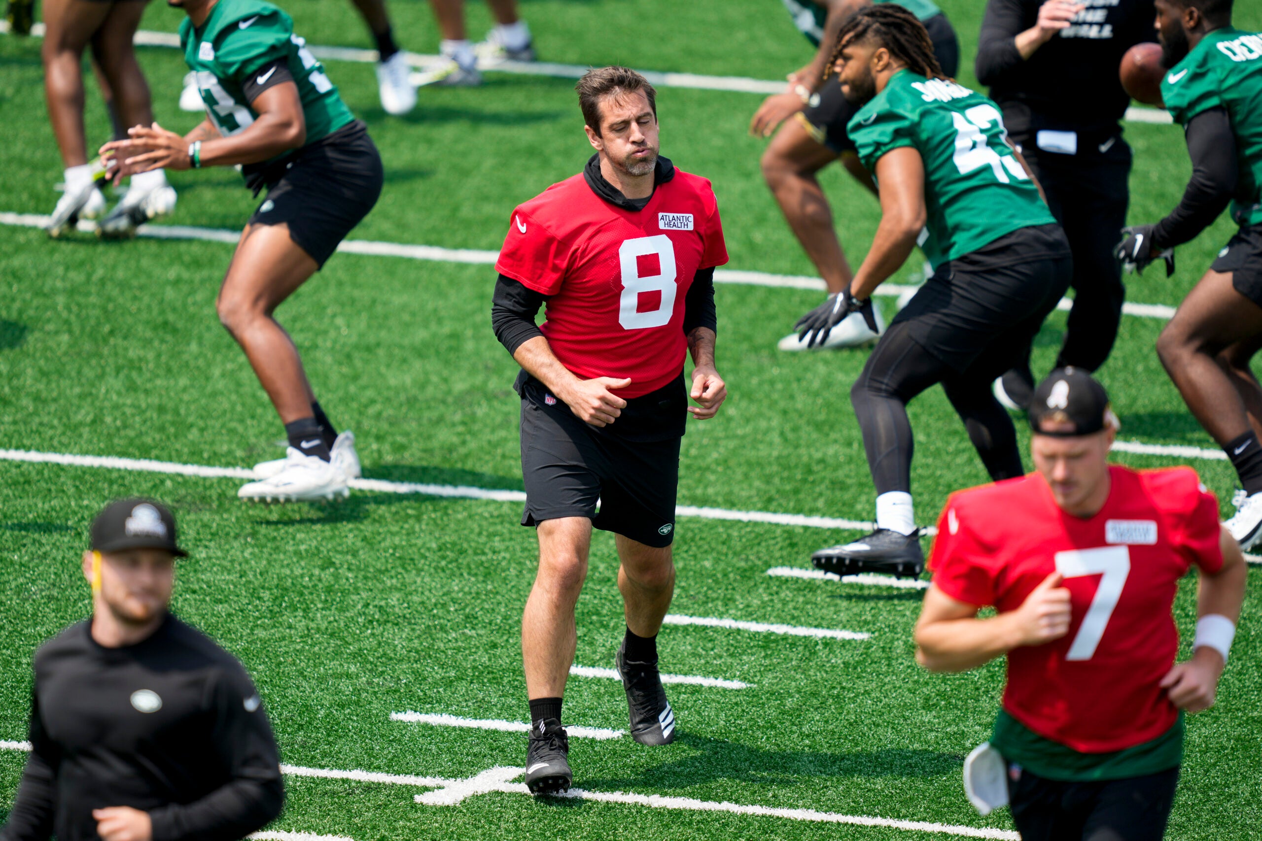 New York Jets quarterback Aaron Rodgers performs stretching drills with his teammates at the NFL football team's practice facility.