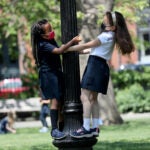 Boston weather , MA - 5/19/2021: Kindergartners from the Park Street School, Michaela Afework, left, and Tesla Long, played on a lamp post in the warm spring weather.