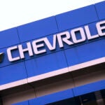 The Chevrolet logo is displayed on the facade of a dealership , Tuesday, Aug. 3, 2021, in Woburn, Mass.