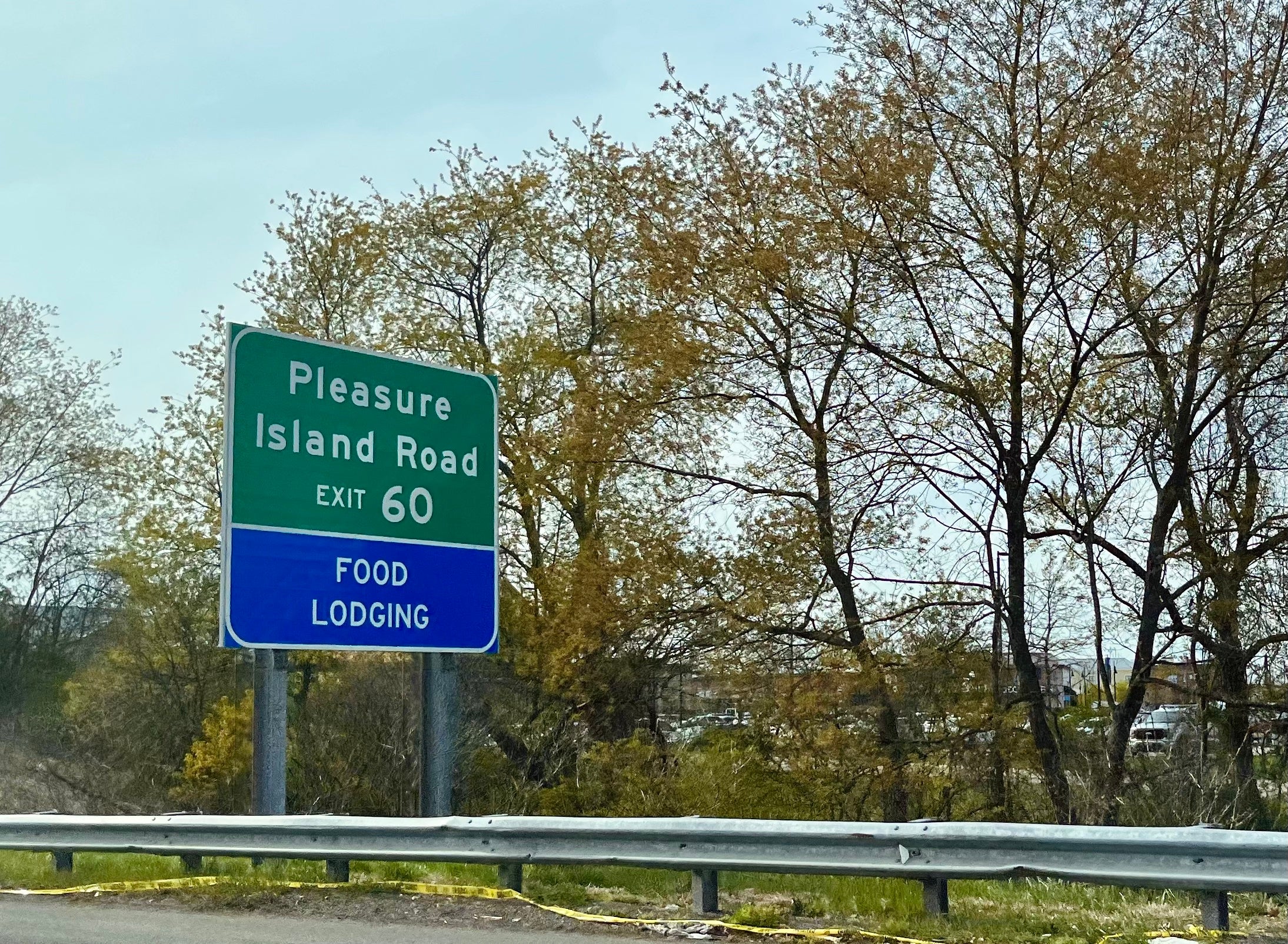 A green highway sign is pictured on the side of the road. It reads "Pleasure Island Road, Exit 60."