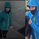A man in a blue windbreaker and a black mask stands on an MBTA train