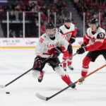 Canada's Connor Bedard, left, skates past Austria's Lukas Horl, right, and Luca Auer during the second period of a world junior hockey championships game in Halifax, Nova Scotia.