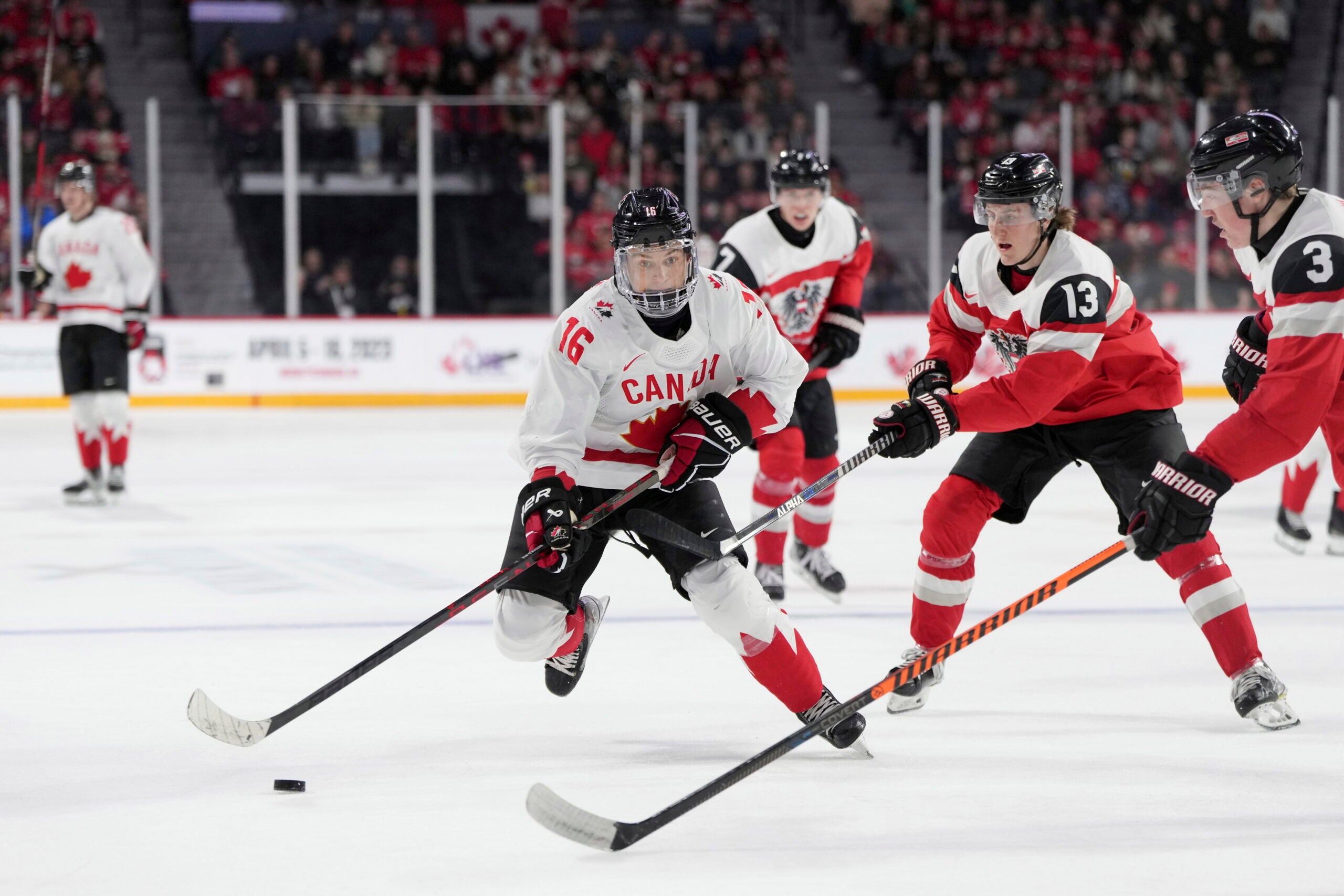 Canada's Connor Bedard, left, skates past Austria's Lukas Horl, right, and Luca Auer during the second period of a world junior hockey championships game in Halifax, Nova Scotia.
