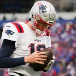 New England Patriots quarterback Mac Jones (10) warms up on the sideline during the first half of an NFL football game against the Buffalo Bills on Sunday, Jan. 8, 2023, in Orchard Park, N.Y.