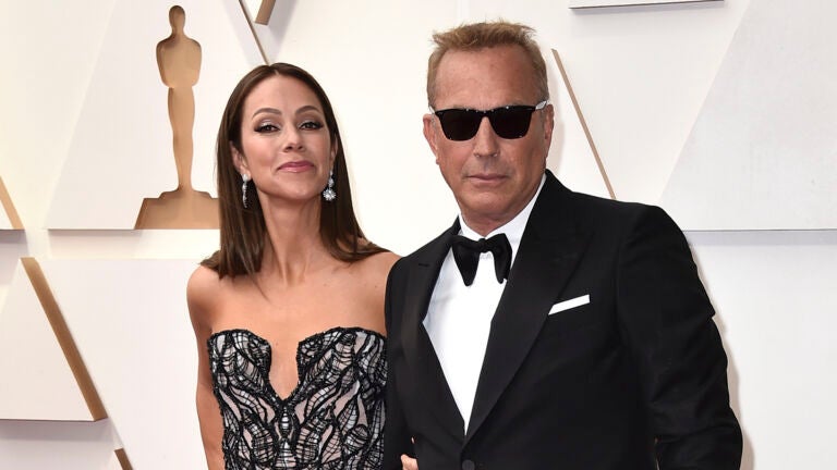 Christine Baumgartner, left, and Kevin Costner arrive at the Oscars, March 27, 2022, at the Dolby Theatre in Los Angeles.