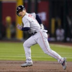Masataka Yoshida breaks from first base, running to the camera's left on the basepaths.