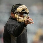 An umpire signals for a strike after being told a strike call through an earpiece during the first inning of a minor league baseball game between the St. Paul Saints and the Nashville Sounds.